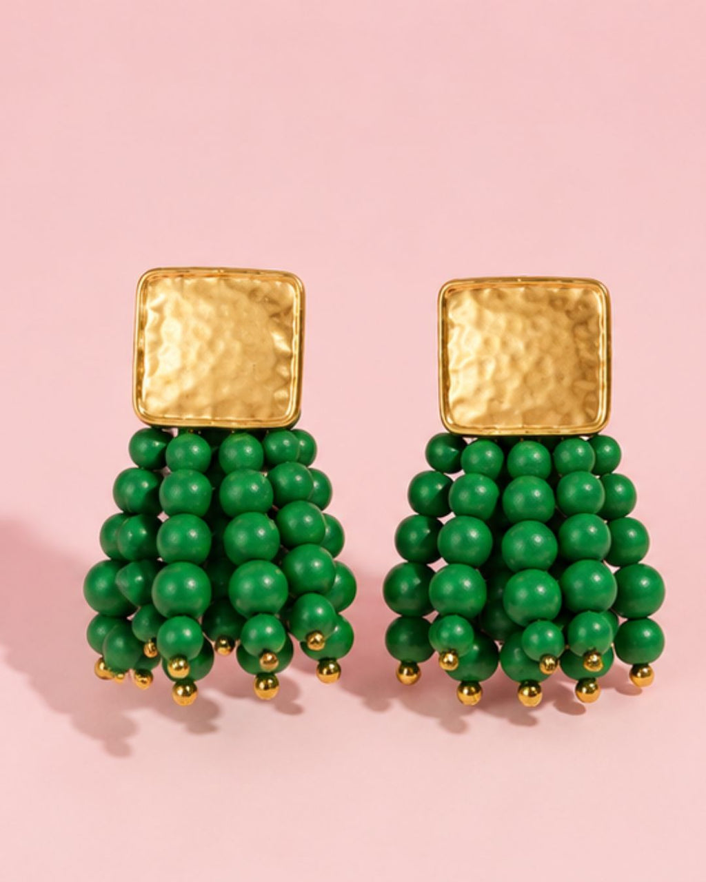 Close-up of green beaded statement earrings with textured gold plated top