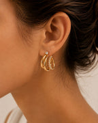 Ciara's Diamond Overlay Studs with white rhinestone detailing and 18K gold plated anti-tarnish finishClose-up of an ear wearing gold hoop earrings with small diamonds.