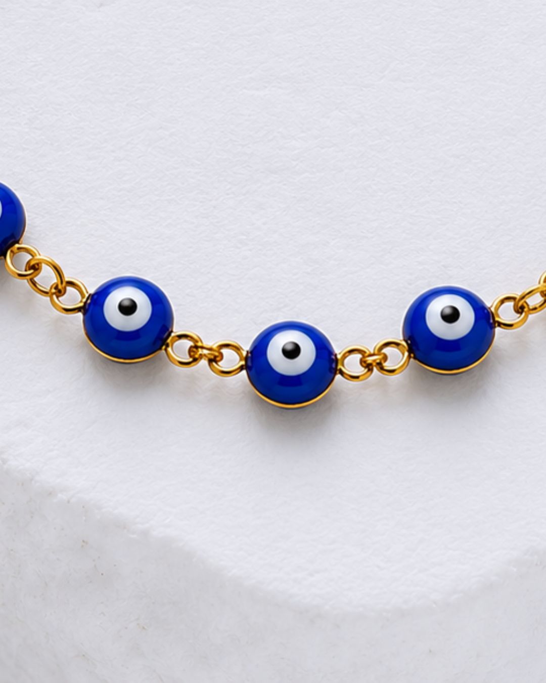 Protective charm bracelet with blue evil eye motifs and gold plated chain