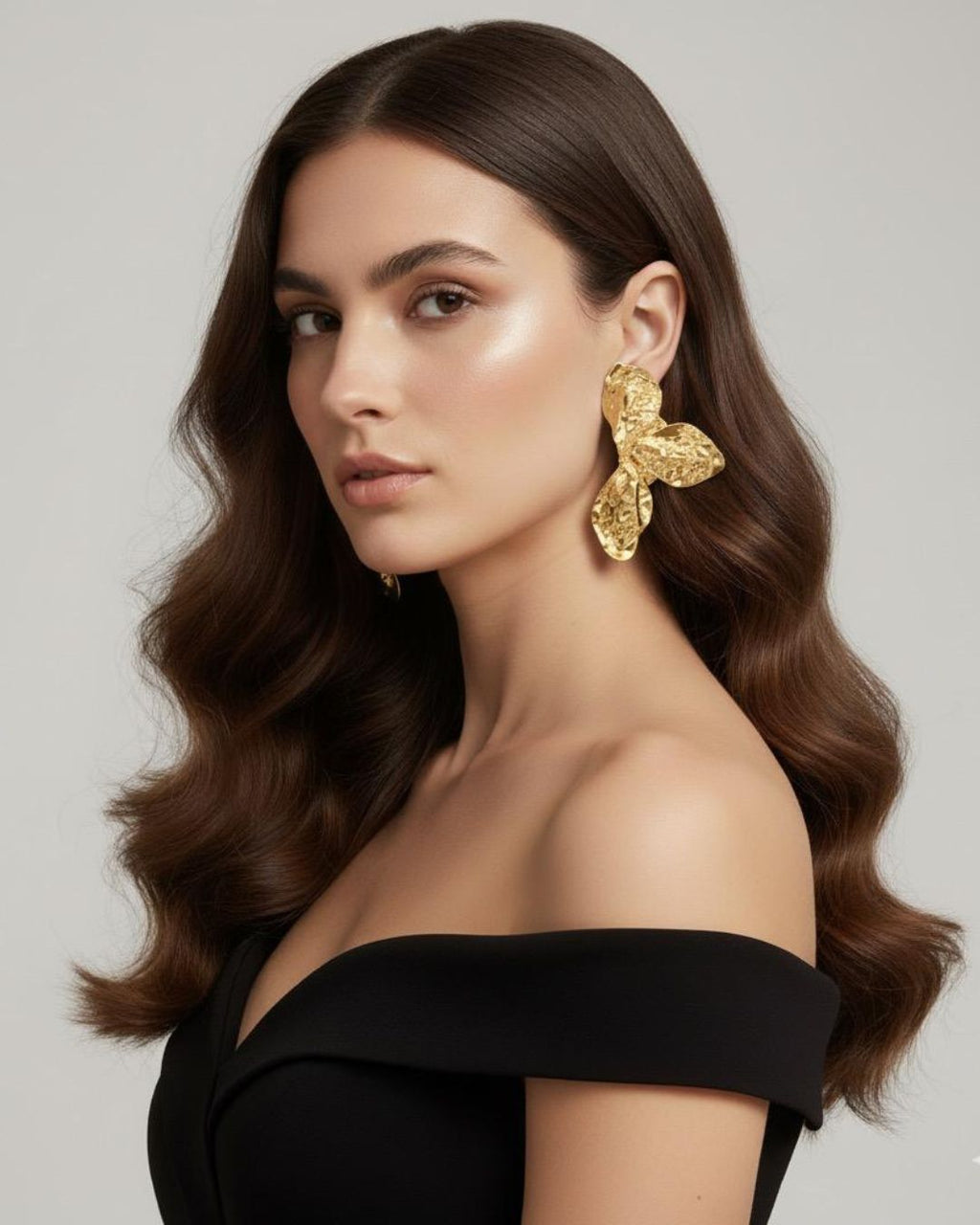 Woman wearing gold Hammered Floral Statement Earrings with textured floral detailing and gold plated finish against a neutral background