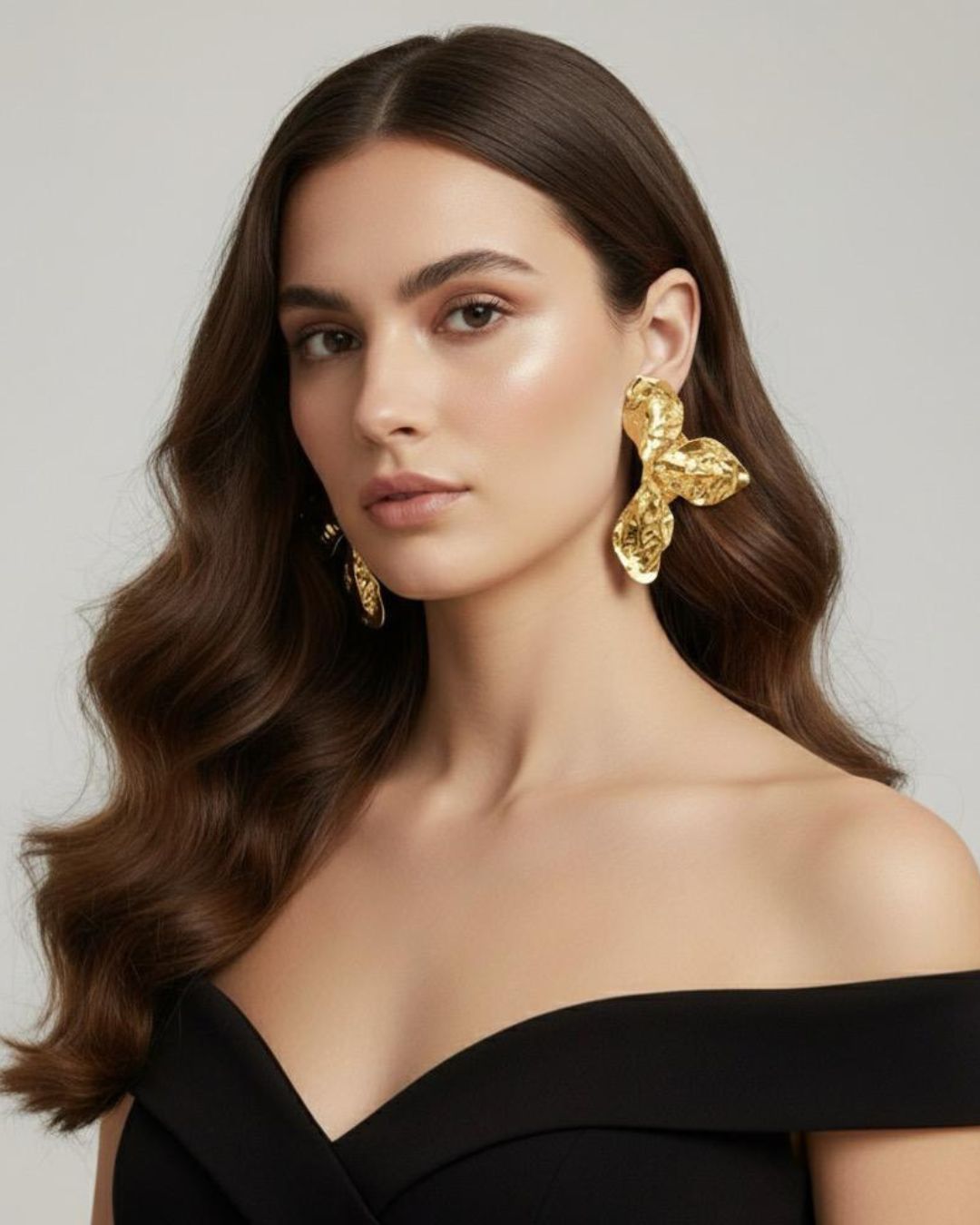 Woman wearing gold Hammered Floral Statement Earrings with textured floral detailing and gold plated finish with a plain background