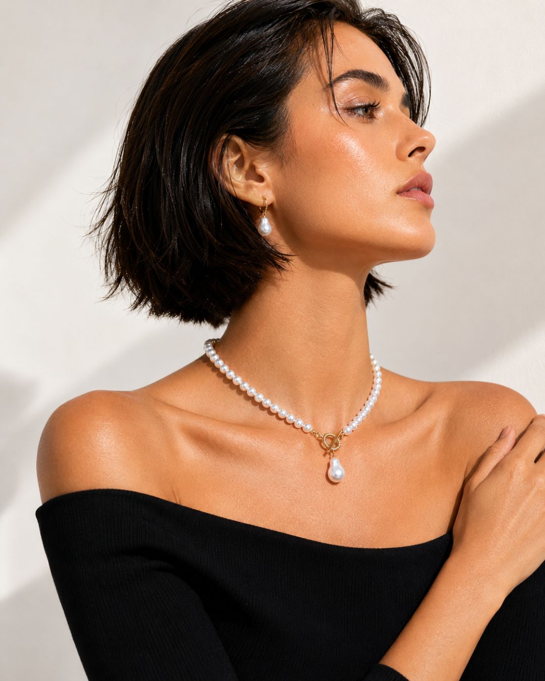Woman wearing a pearl necklace and earrings against a neutral background Detailed view of Luna Drop Pearl Necklace featuring toggle clasp and statement pearl drop pendant