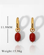 Gold earrings with red beads on a white background, showing measurements and weight.