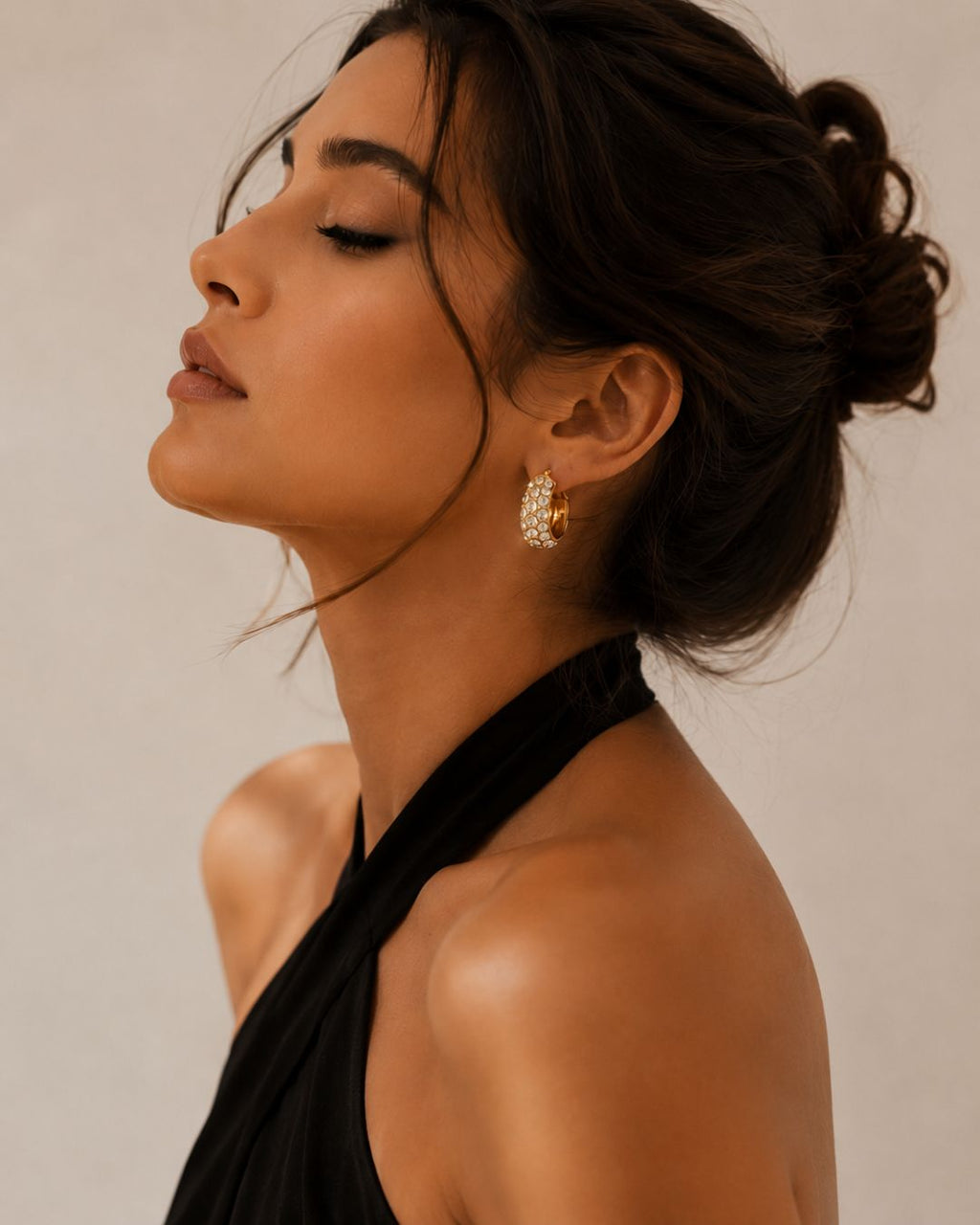 White Rhinestone Diamond Huggie Hoop Earrings for elegant party and festive styling. Woman wearing a black halter top with a neutral background