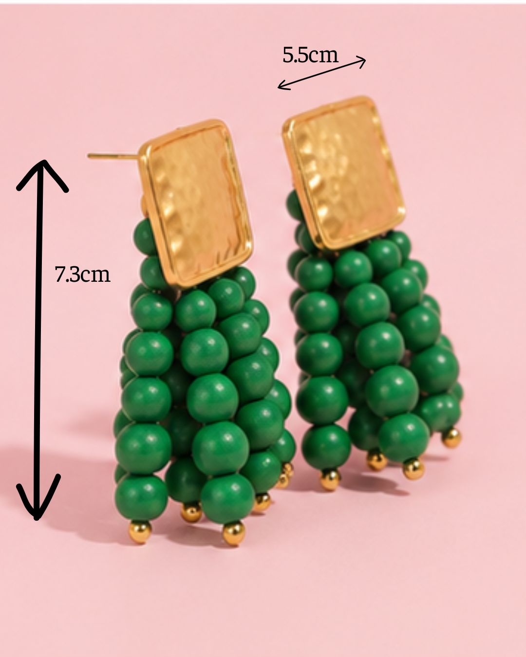 Green beaded earrings with gold accents on a pink background, showing measurements.